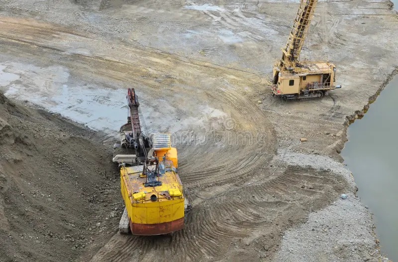 Vista aérea de excavadora y equipo perforador en faena minera